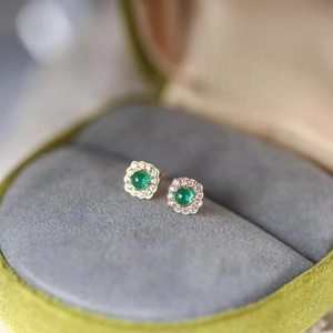 Macro shot of S925 silver emerald earrings with zircon halo in luxury velvet jewelry box