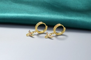 Détail d'une boucle d'oreille papillon en or 18K avec zircons colorés sur soie verte