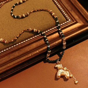 Detail van tijgeroog kralenketting met vergulde pony hanger op vintage lederen basis