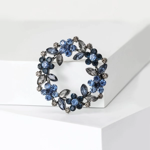Macro detail of wreath brooch with blue and grey rhinestones on polished metal base