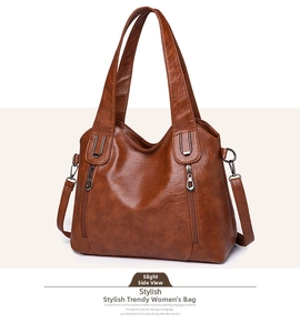 Detail view of the brown leather tote bag showing decorative zippers and metal hardware