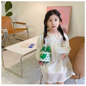 Close-up of a child's green heart bucket bag with golden chain and bow detail