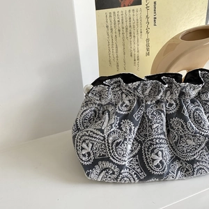 Detailed view of gray velvet clutch with white paisley embroidery and pearl bead detail