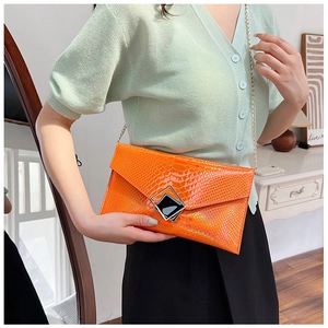 Dettaglio pochette arancione motivo coccodrillo con catena dorata e fibbia quadrata in metallo