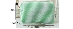 Detail view of striped seersucker makeup bag with 16x9x9cm dimensions and green pattern