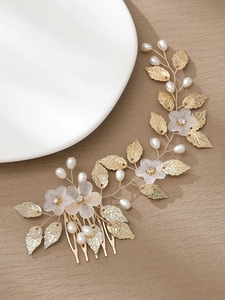 Detail of golden bridal hair comb with acrylic flowers and pearl leaf accents