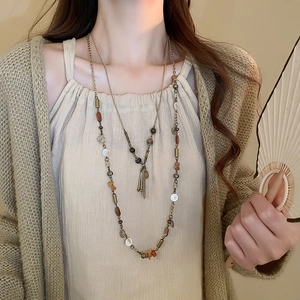 Dettaglio della collana lunga boho vintage con perline a strati e nappe di monete