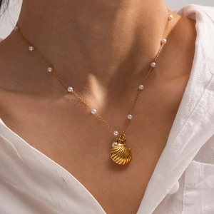 French ocean pearl necklace with gold shell pendant worn by model on white shirt