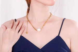 Detailed view of a gold titanium necklace featuring a pearl pendant and mixed chain design