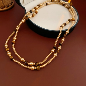 Detailed macro of vintage tiger eye stones and golden pearls on a double layer necklace