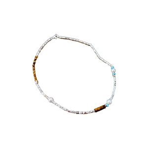 Minimalist pearl and tiger eye stone necklace with silver beads on white background