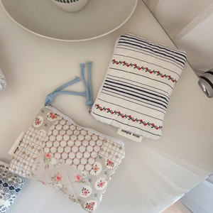 Quilted floral mini pouches with blue lanyards and silver zippers on a white desk