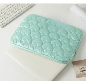 Macro shot of mint green laptop sleeve with heart quilted stitching on a laptop