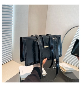 Detail of glossy black patent leather surface and golden metal hardware on handbag