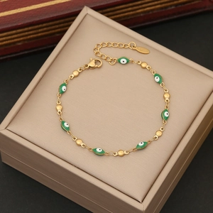 Detail of gold evil eye bracelet with green enamel beads and lobster clasp on jewelry box