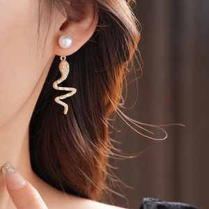 Macro detail of 14K gold plated serpent earrings with pavé zircons and pearls