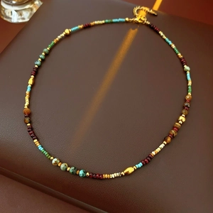 Macro detail of bohemian beaded necklace with turquoise, red beads and gold lobster clasp