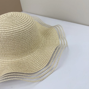 Close-up of beige straw sun hat with detailed sheer tulle stripe mesh on wide brim