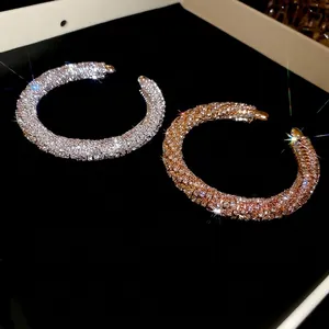 Sparkling crystal-encrusted gold and silver hoop earrings on a black velvet background