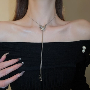 Detail view of a silver butterfly pendant necklace with elegant tassel chain on a model