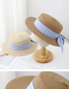 Detail view of woven straw boater hats with blue plaid ribbon and side bow accent