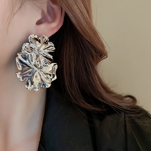 Close-up of a model wearing large silver fan-shaped floral earrings with a mirror finish