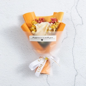 Close-up of a mini dried flower bouquet with a white rose and orange wrapping paper
