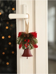 Close-up of rustic Christmas bell with red bow, pine cones and berries on door handle