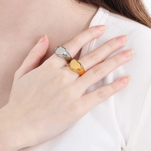 Detail showing polished heart signet rings in gold and silver finishes on a model's hand