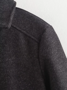 Detail shot of the shoulder and round neckline on a dark grey textured wool jacket