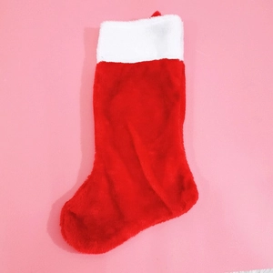 Classic red plush Christmas stocking with white faux fur trim on a soft pink background