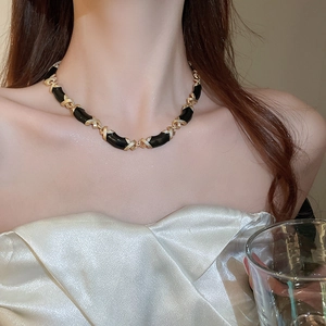 Détail d'un collier vintage avec maillons dorés en forme de X et accents noirs courbés