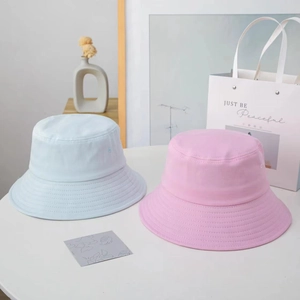 Detail of light blue and pink cotton sun hats on a minimalist white table setup