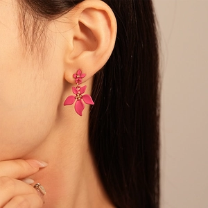 Gros plan d'un mannequin portant des boucles d'oreilles double fleur rose mat