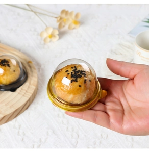 Detail of a transparent dome lid and gold base for single egg yolk pastry packaging