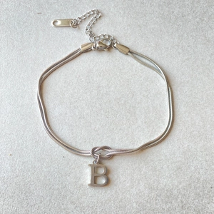 Detail of silver stainless steel herringbone chain bracelet with letter B initial pendant