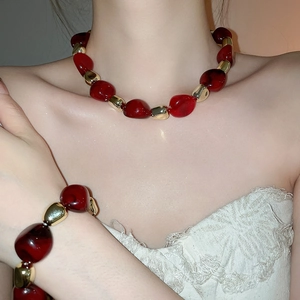 Detail of red acrylic beads and golden metallic spheres on necklace and bracelet set