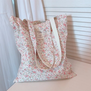 Detailed close-up of floral canvas tote bag featuring small pink flowers and cloth label