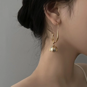 Minimalist geometric gold earrings with white pearl drop on female model's ear