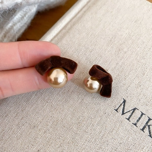 Detailed view of dark brown flocked bowknot earrings with a polished gold pearl charm