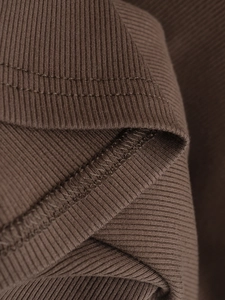 Détail du tissu en maille côtelée marron foncé montrant la texture et les coutures