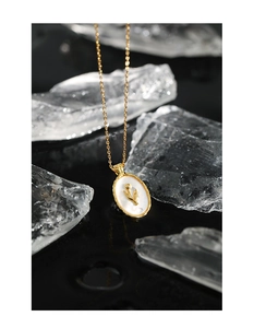 Macro detail of tulip relief on oval shell pendant with elegant gold plated link chain
