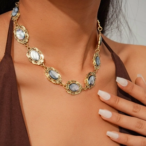 Close-up of vintage gold embossed oval shell necklace worn on a model's neck