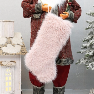 Pink faux fur Christmas stocking held by Santa against festive holiday tree background