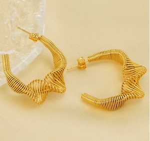 Detailed view of irregular wavy gold coiled spring earrings with wire wrap texture