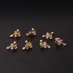 Boucles d'oreilles nœuds dorés avec pierres de zircone colorées sur fond noir