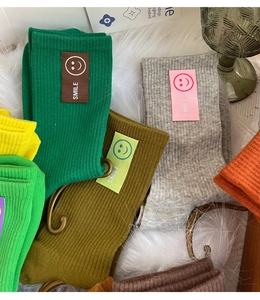 Gros plan de chaussettes en coton colorées en vert, jaune et orange sur une surface douce