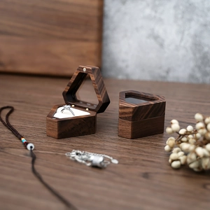 Detail of walnut wood triangular ring boxes featuring a silver diamond ring inside