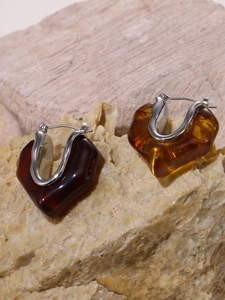 Close-up of resin amber earrings with silver metal clasps on natural stone display