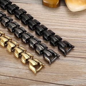 Polished gold and black titanium steel dragon scale chains on a minimalist wooden surface